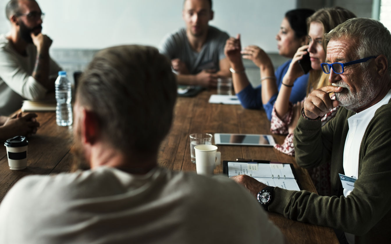 Mennesker, der sidder rundt om et bord og snakker
