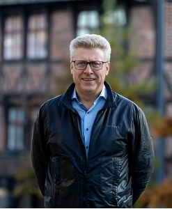 Mand i sort jakke og blå skjorte