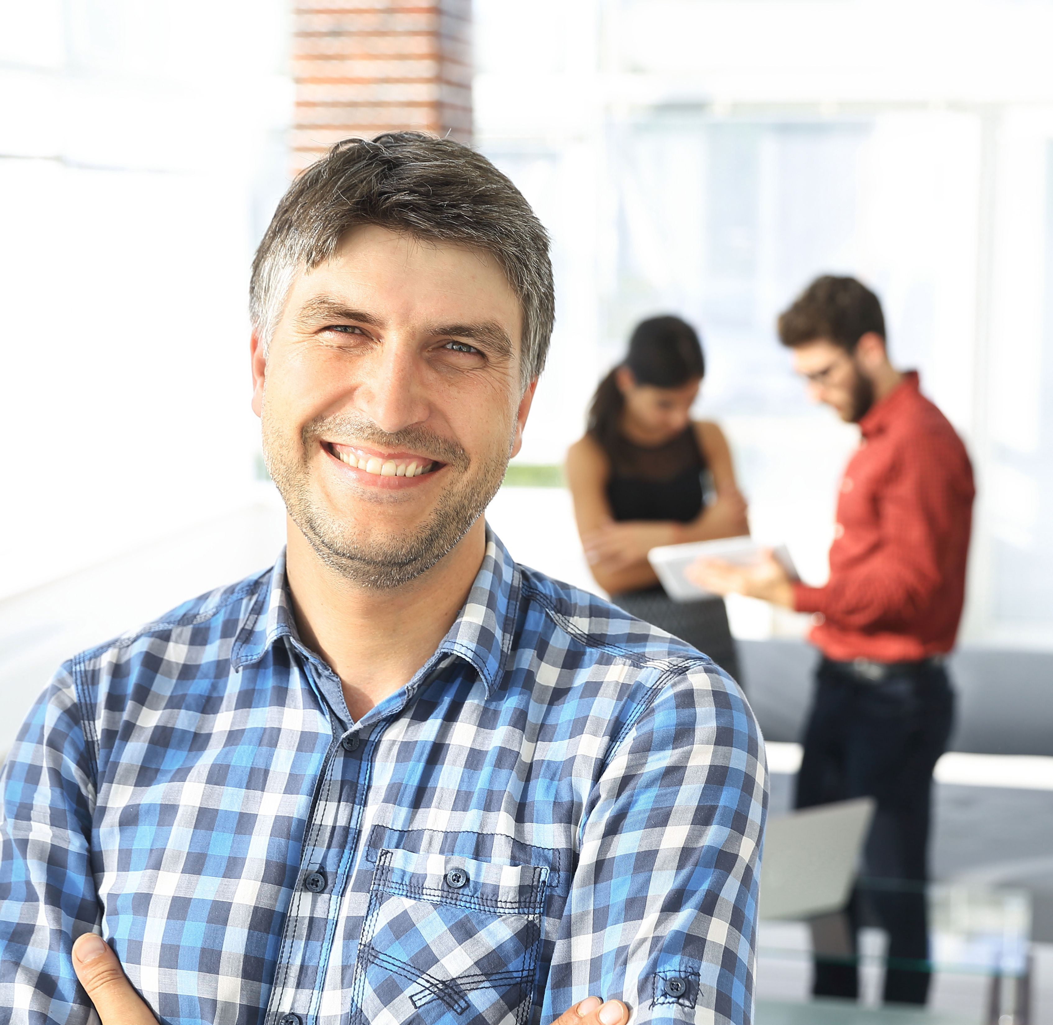 Smilende mand med kvinde og mand i baggrunden