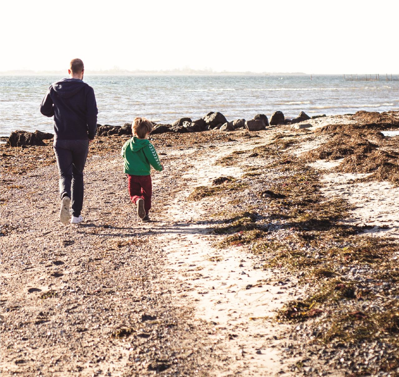 Far og barn løber på stranden
