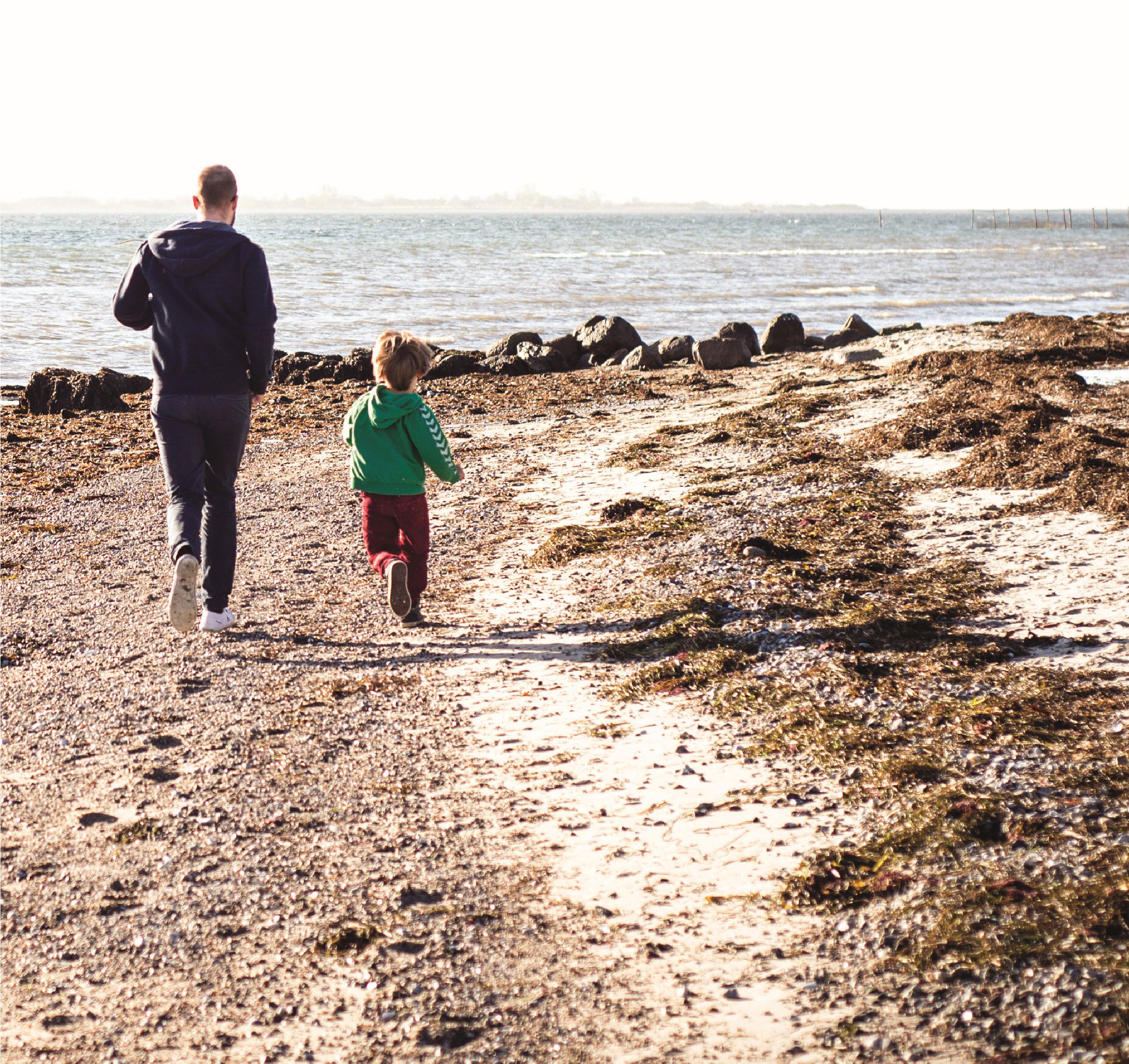 Far og barn løber på stranden