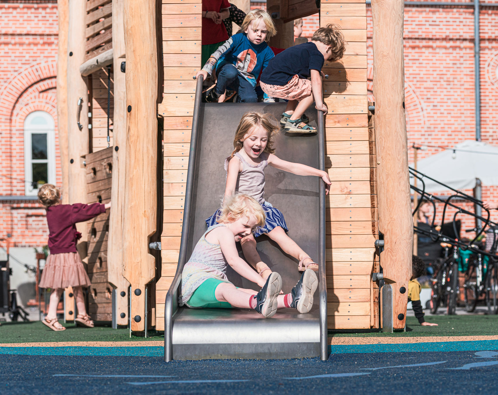 Børn rutcher ned af en rutchebane på en legeplads