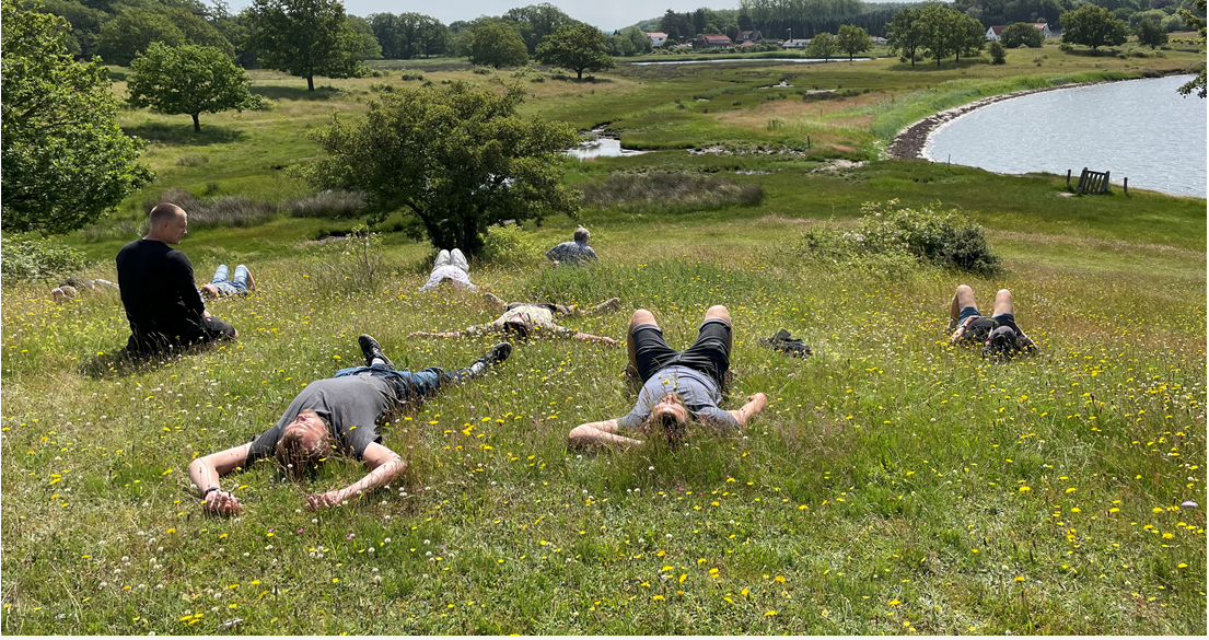 Mænd, der ligger på græsmark - mens fagperson sidder op.