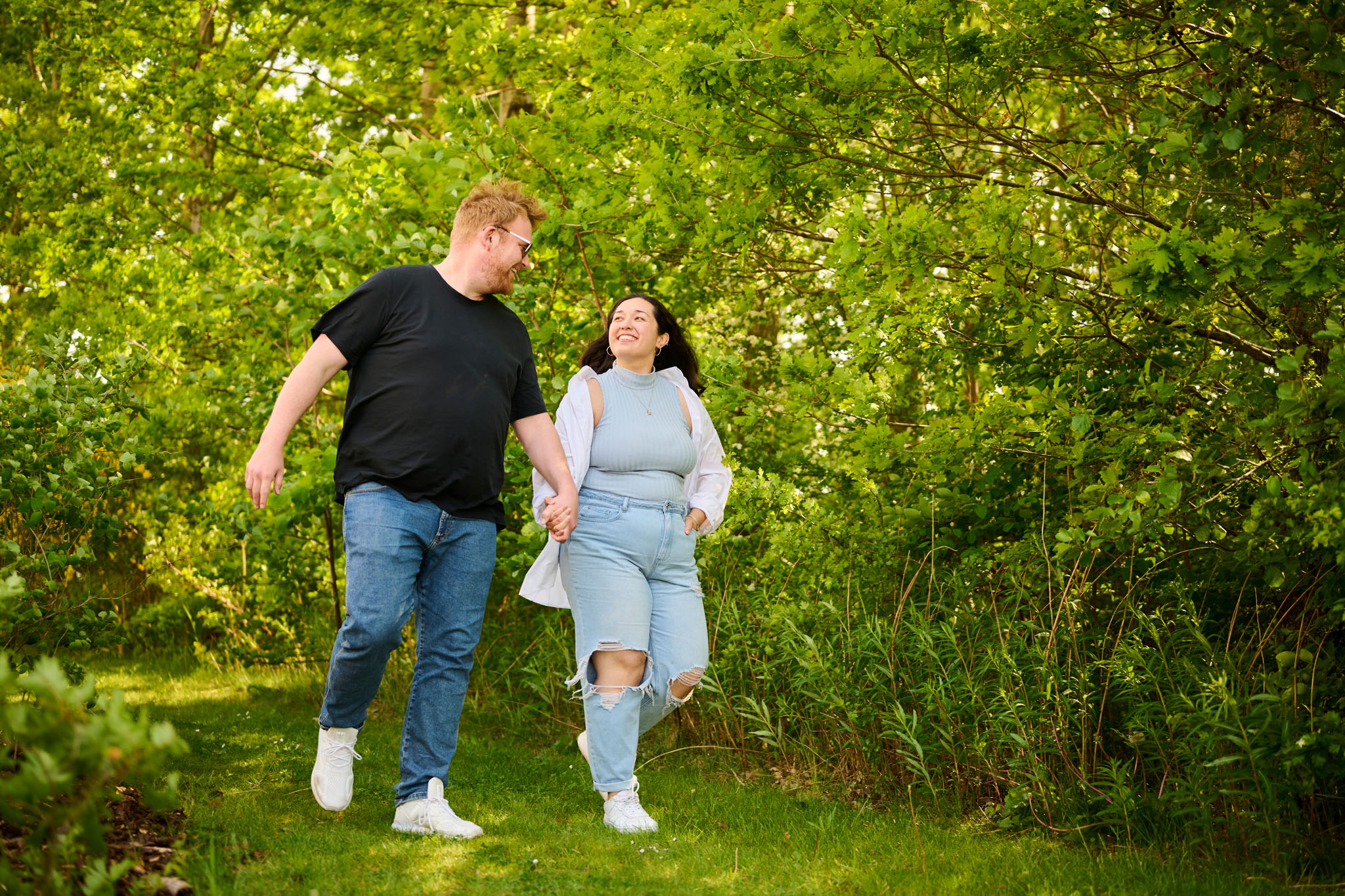 Mand og kvinde går med hinanden i hånden i grønne omgivelser