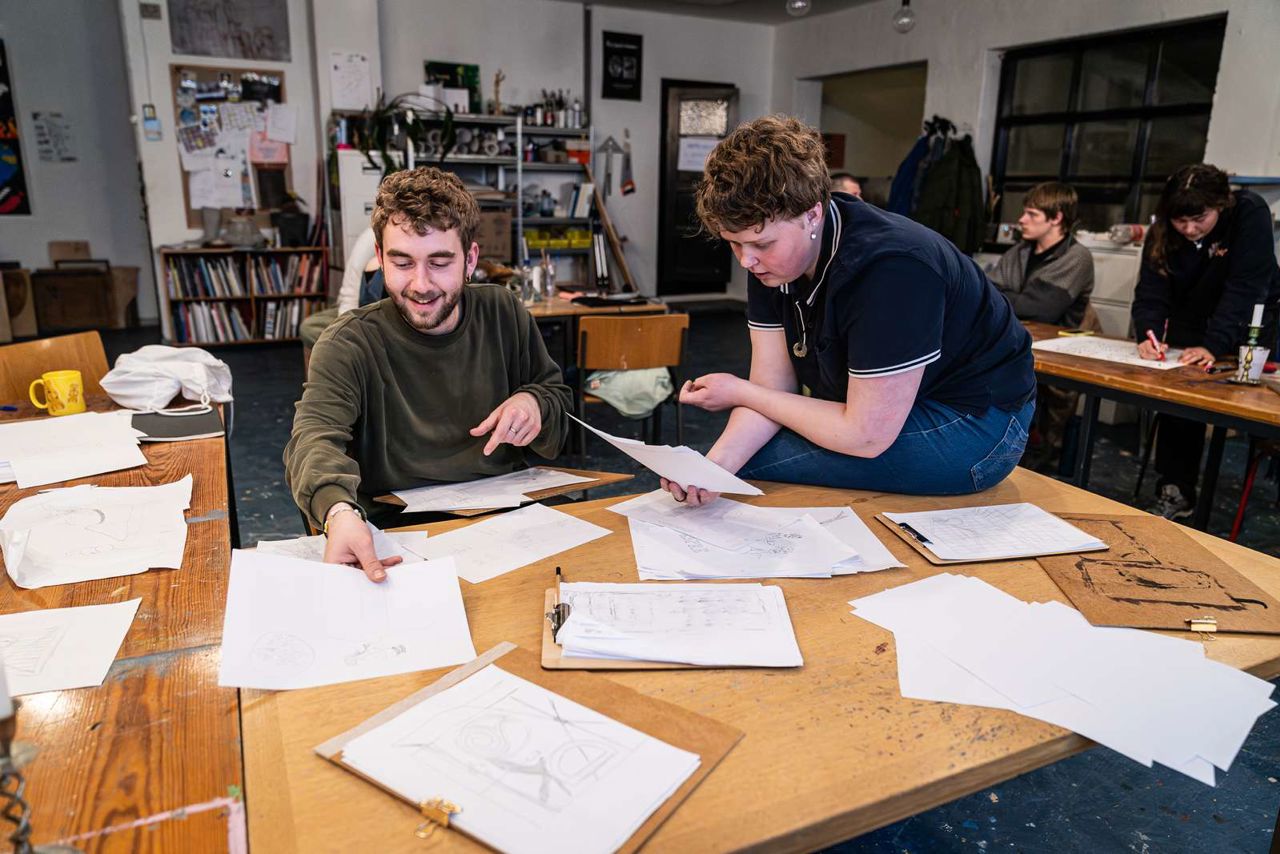 2 unge kunstnere deler tegninger ved et bord