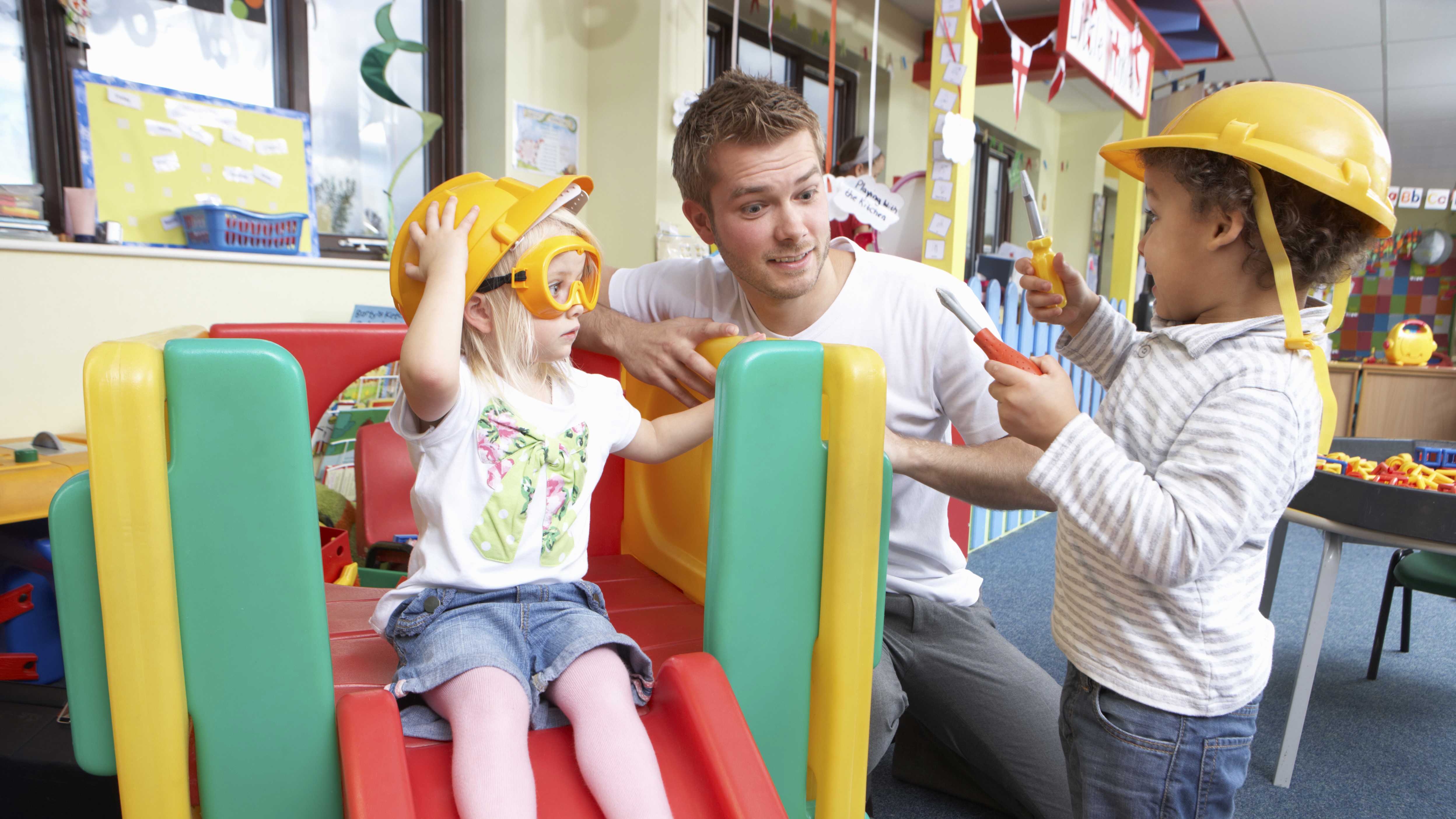 To børn som leger sammen med en mandlig pædagog